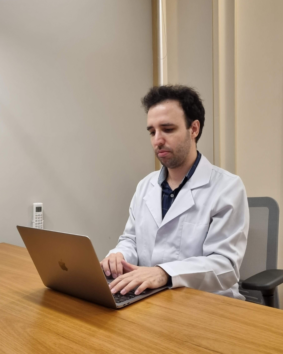 Foto do Neurologista Anderson Pelichek. Homem branco, cabelos curtos castanhos, usando jaleco branco e esteto no pescoço.